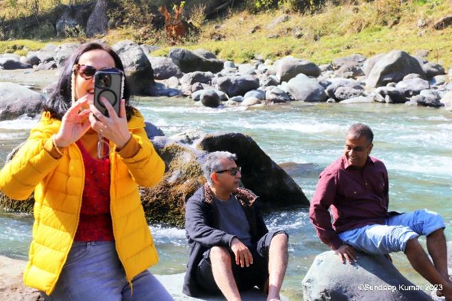 A person taking a picture of a group of people sitting on rocks

Description automatically generated